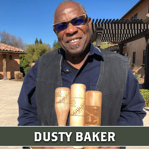 Dusty Baker smiling behind three wooden Dugout Mugs baseball bat mugs.