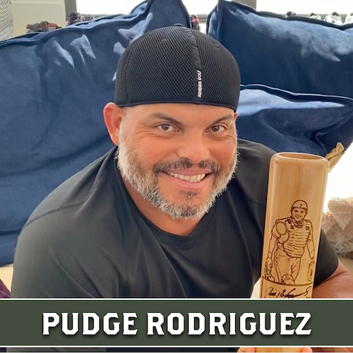 Pudge Rodriguez smiling and holding a wooden Dugout Mugs baseball bat mug engraved with a portrait.