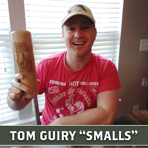 Tom Guiry smiling and holding up a wooden Dugout Mugs baseball bat mug.