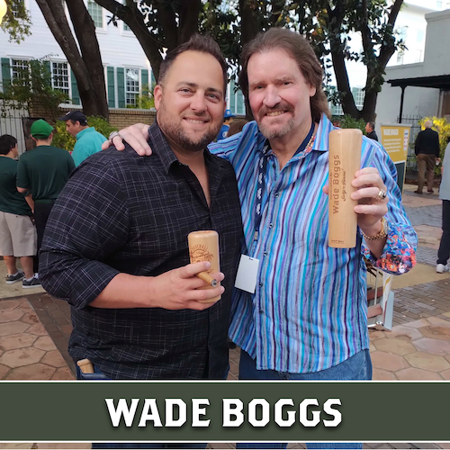 Wade Boggs posing outdoors beside another man, both holding wooden Dugout Mugs baseball bat mugs.
