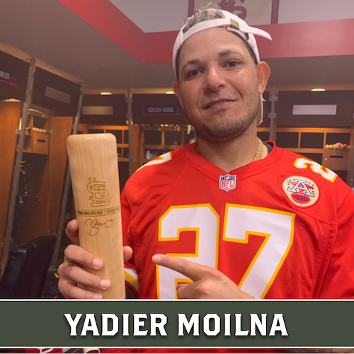 Yadier Molina wearing a red number 27 jersey and holding a wooden Dugout Mugs baseball bat mug.