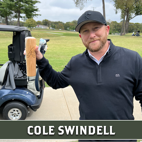 Cole Swindell holding up a wooden Dugout Mugs baseball bat mug beside a golf cart.